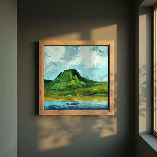 Lurig Mountain, Cushendall framed print in a natural oak frame on a dark green wall beside a window, dappled plant shadow