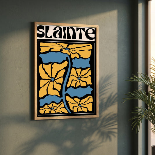 Sláinte framed print in a natural oak frame on a dark green wall beside a window, dappled plant shadow