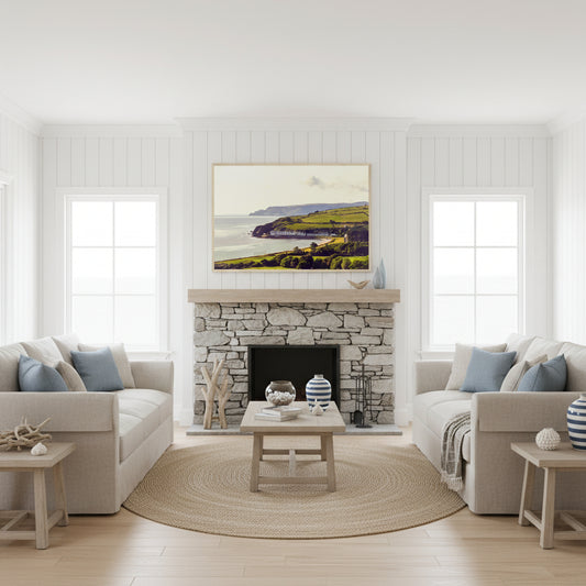 Cushendun framed print above a stone fireplace in a bright coastal living room with white panelled walls, linen sofas and soft natural light.
