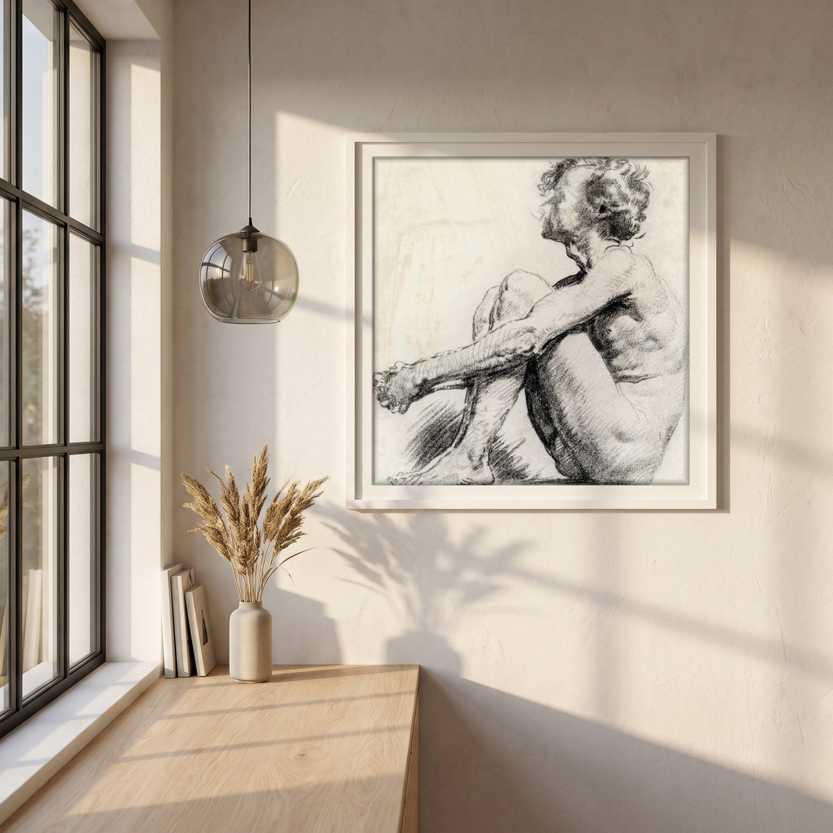 A Seated Male Figure by Sarah Purser framed print in a white frame on a plaster wall above an oak worktop in a bright Scandinavian kitchen