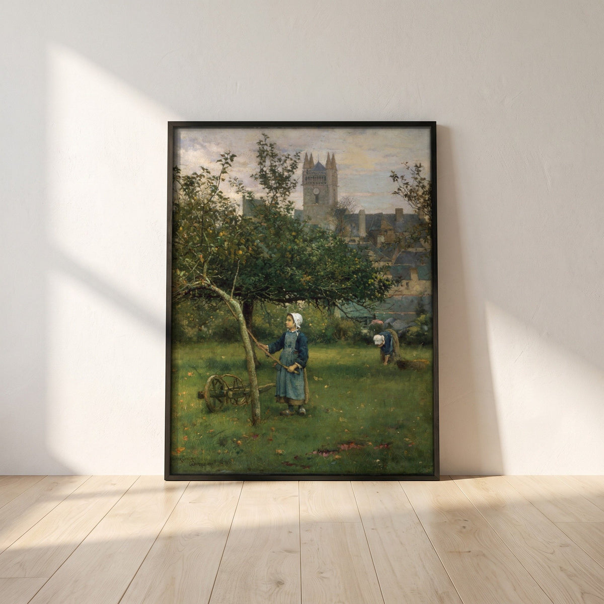 Apple Gathering, Quimperlé framed print in a black frame leaning against a white plaster wall on oak floorboards in morning light