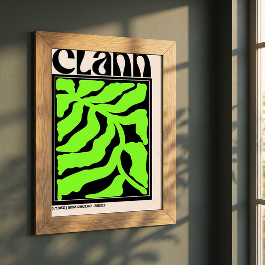 Clann framed print in a natural oak frame on a dark green wall beside a window, dappled plant shadow