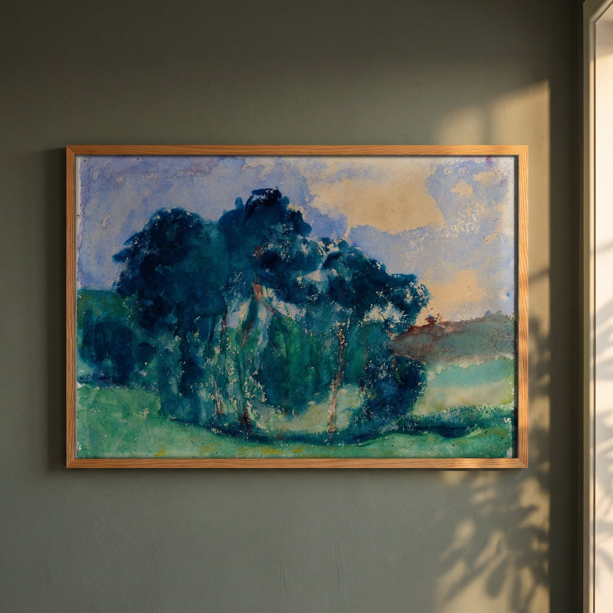 Clump of Trees, Rochefort-en-Terre framed print in a natural oak frame on a dark green wall beside a window, dappled plant shadow