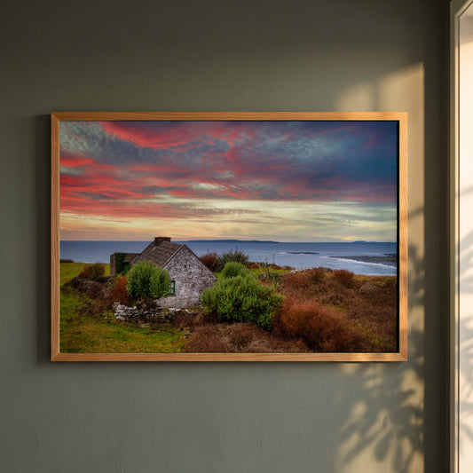Doolin, Co. Clare framed print in a natural oak frame on a dark green wall beside a window, dappled plant shadow