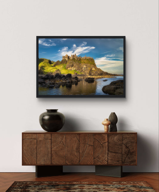 Dunluce Castle cliffs print in a black frame above a carved wooden sideboard