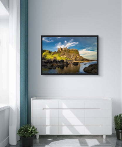 Dunluce Castle cliffs print in a black frame on a grey wall above a white cabinet