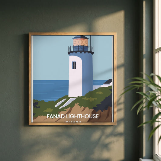 Fanad Head Lighthouse framed print in a natural oak frame on a dark green wall beside a window, dappled plant shadow