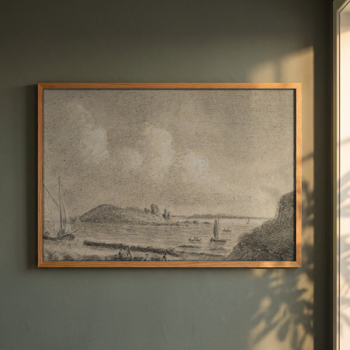 Ireland's Eye and Lambay Island from Howth framed print in a natural oak frame on a dark green wall beside a window, dappled plant shadow