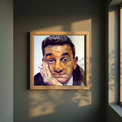 John B. Keane framed print in a natural oak frame on a dark green wall beside a window, dappled plant shadow