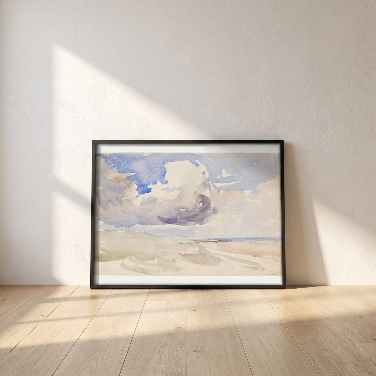 Low Clouds over a Beach framed print in a black frame leaning against a white plaster wall on oak floorboards in morning light