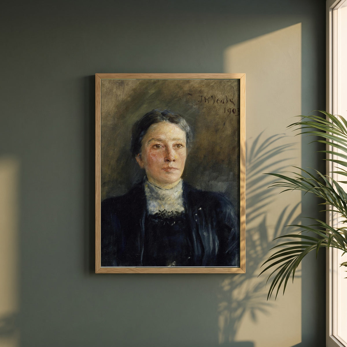 Portrait of Augusta Gregory framed print in a natural oak frame on a dark green wall beside a window, dappled plant shadow
