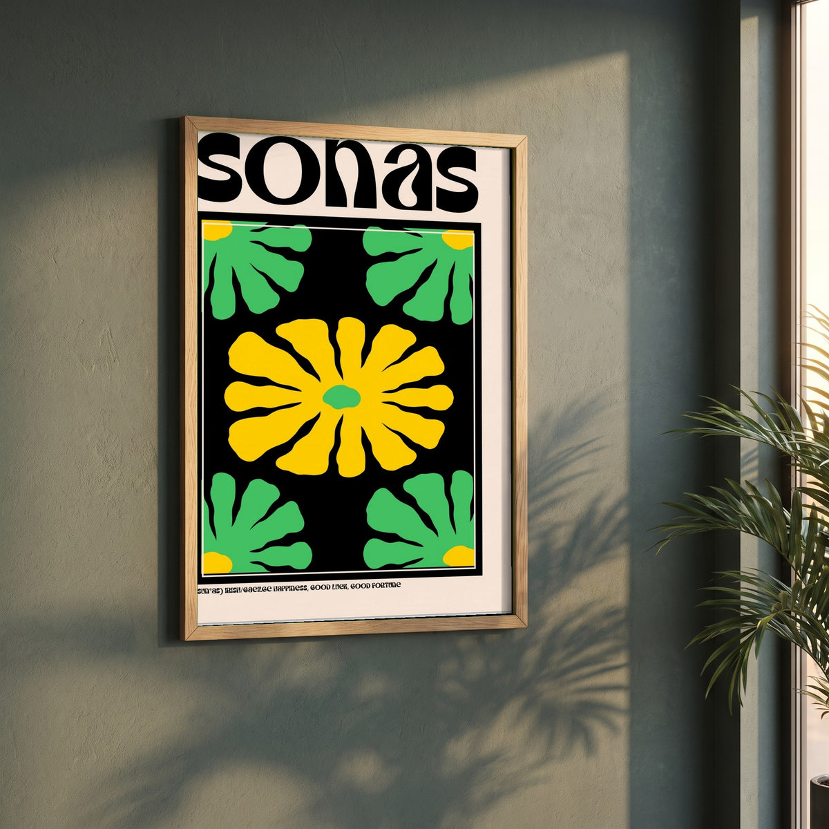 Sonas framed print in a natural oak frame on a dark green wall beside a window, dappled plant shadow