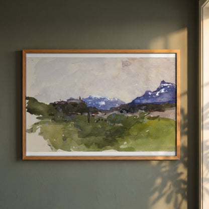The Pyrenees Mountains framed print in a natural oak frame on a dark green wall beside a window, dappled plant shadow