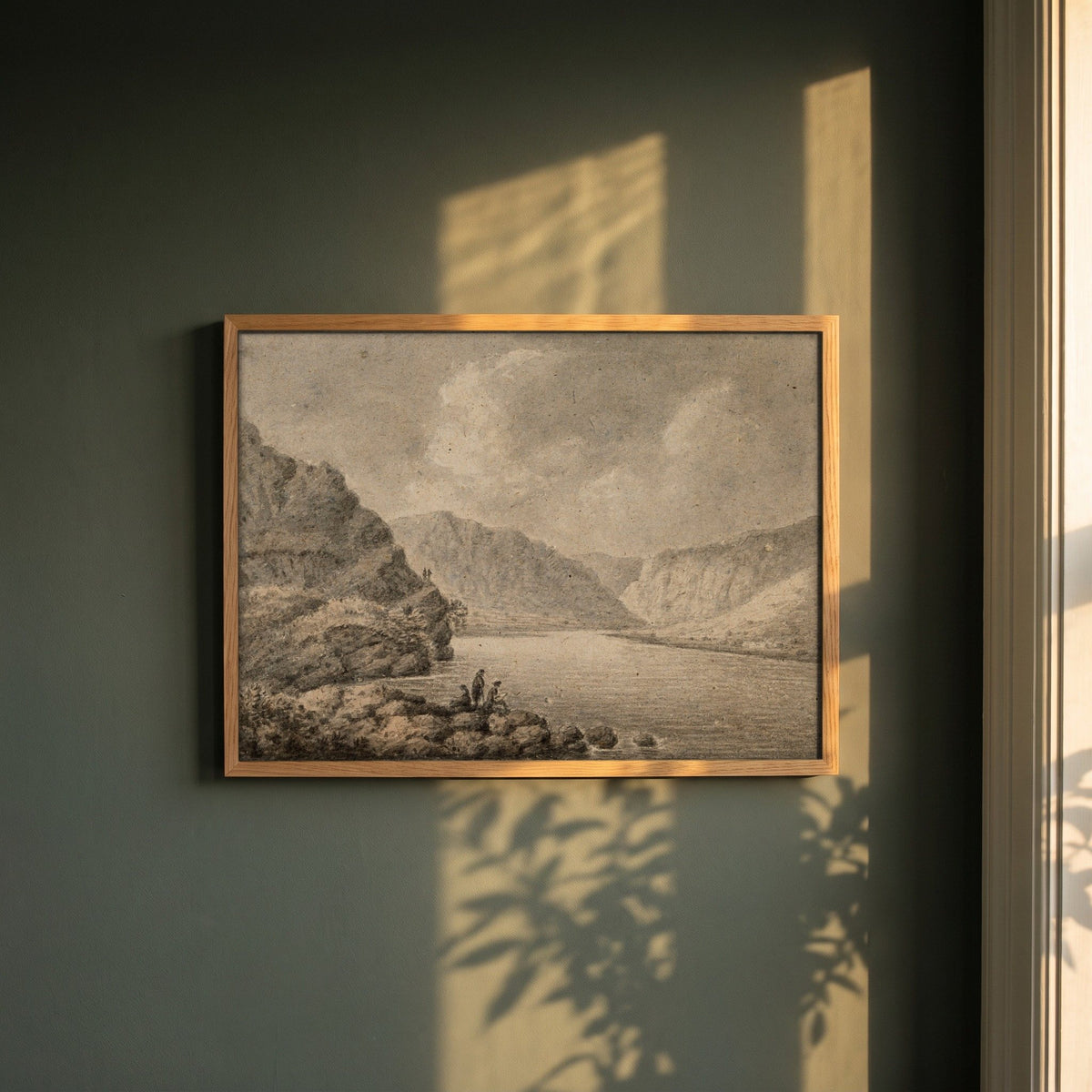 The Upper Lake, Glendalough framed print in a natural oak frame on a dark green wall beside a window, dappled plant shadow