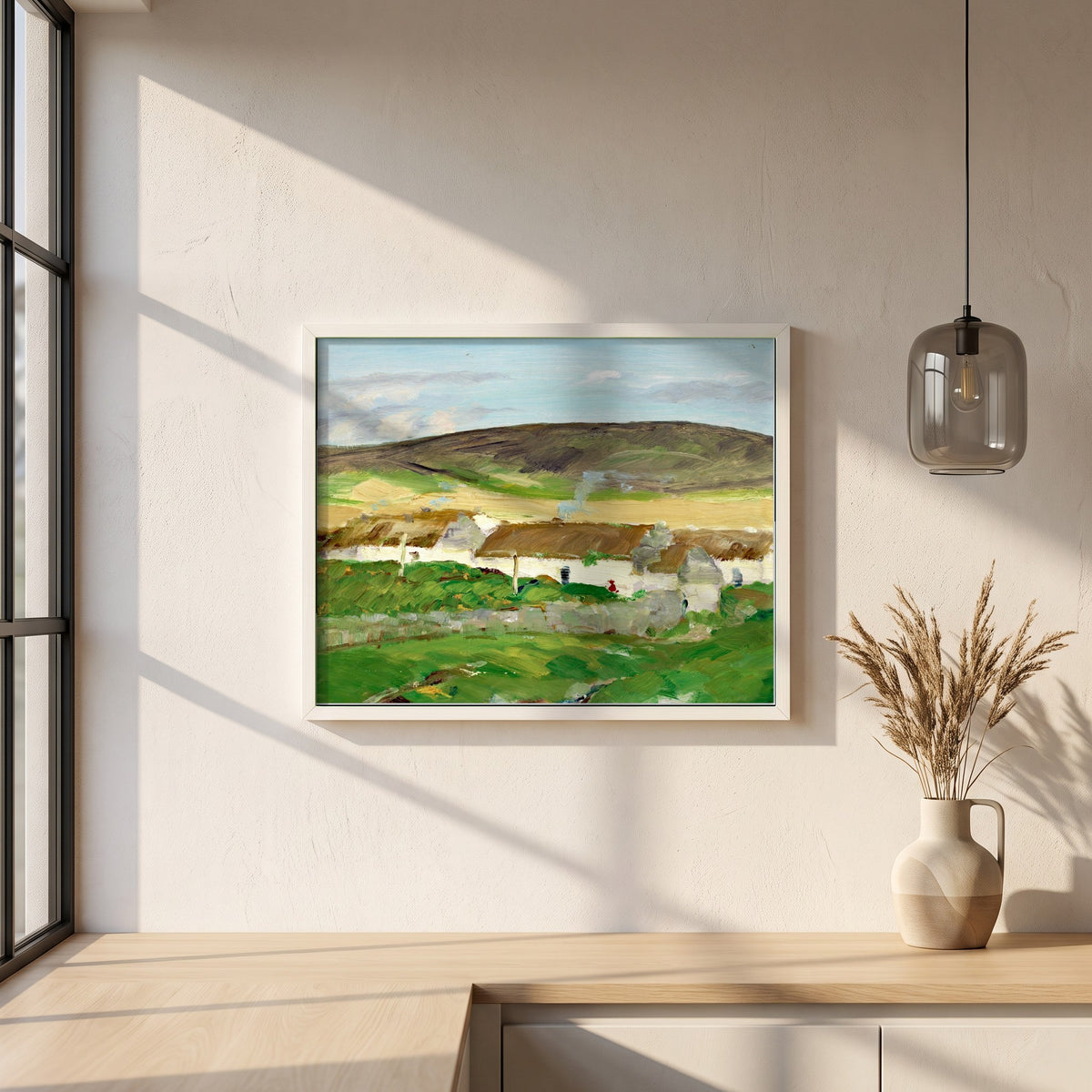 The White Cottage framed print in a white frame on a plaster wall above an oak worktop in a bright Scandinavian kitchen